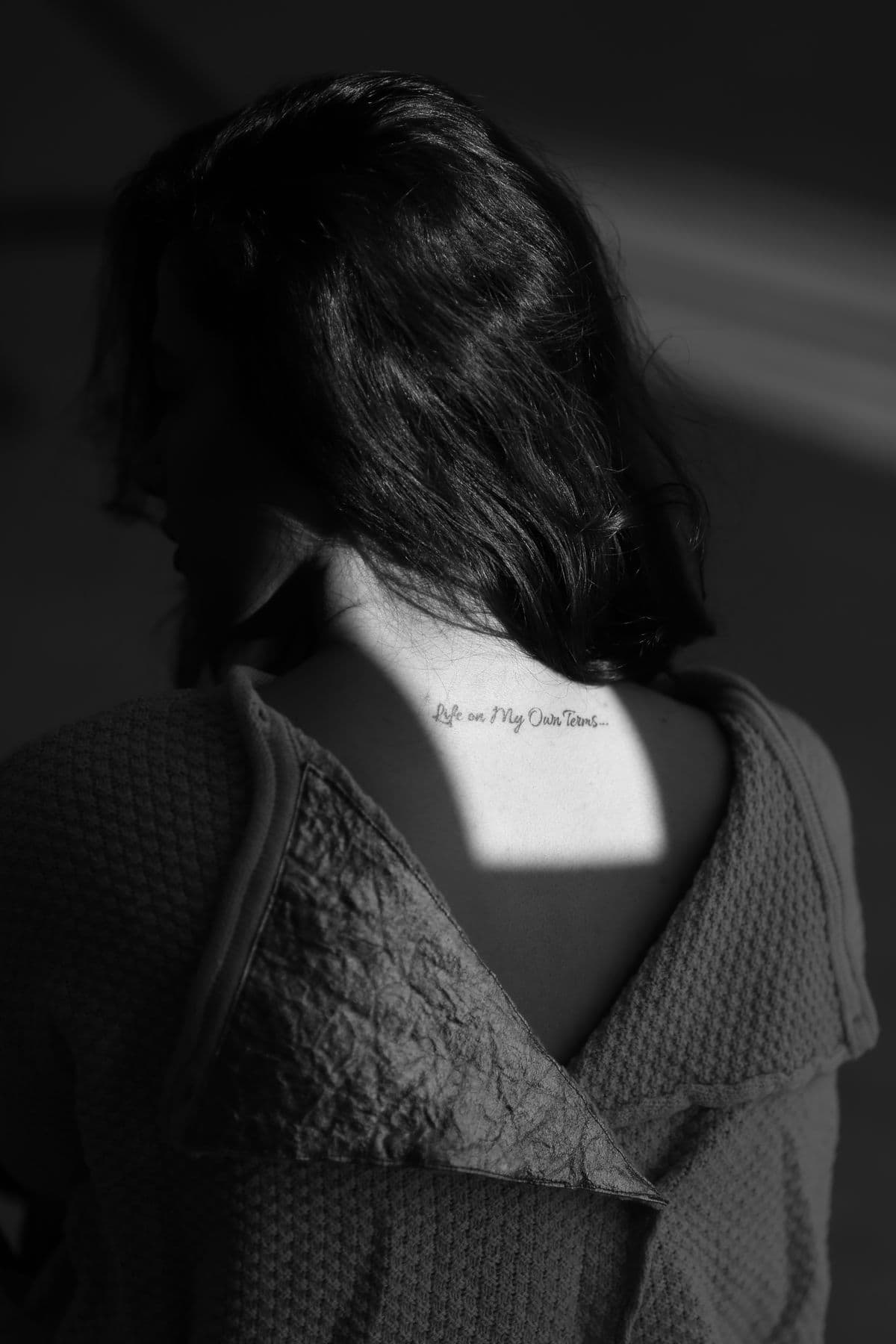Fine script lettering across the upper back, just below the hairline